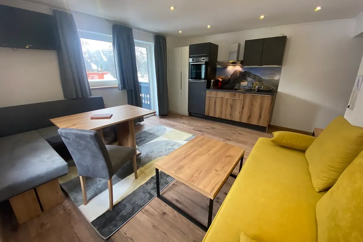 Wohnbereich im Apartment Großglockner mit Couch Essbereich und Küche bei GRUBERS Hotel Apartments Gastein