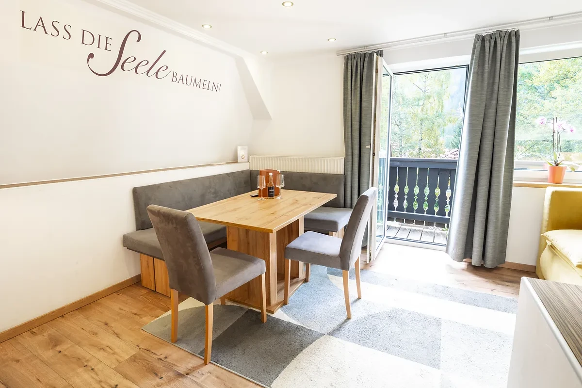 Essbereich im Apartment mit offener Balkontür und Blick ins Grüne bei GRUBERS Hotel-Apartments Gastein – Urlaub mit Hund