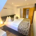 Schlafzimmer im Familienzimmer Bockhartsee mit Doppelbett eigenem TV und Blick in den Gang in Bad Gastein