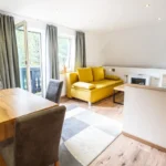 Wohnbereich im Familienzimmer Bockhartsee für 5 Personen mit Schlafsofa Essbereich und Gartenblick in Bad Gastein