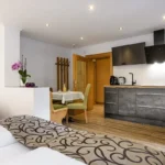 Studio Reedsee mit Einzelbett und Blick auf die voll ausgestattete Küche mit Essbank in Bad Gastein