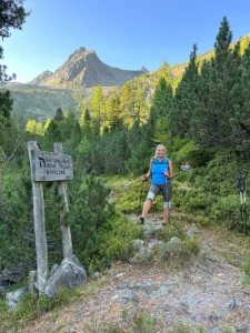 Gerti beim Wandern im Nationalpark Hohe Tauern neben einem Holzschild mit Hinweis auf die Kernzone
