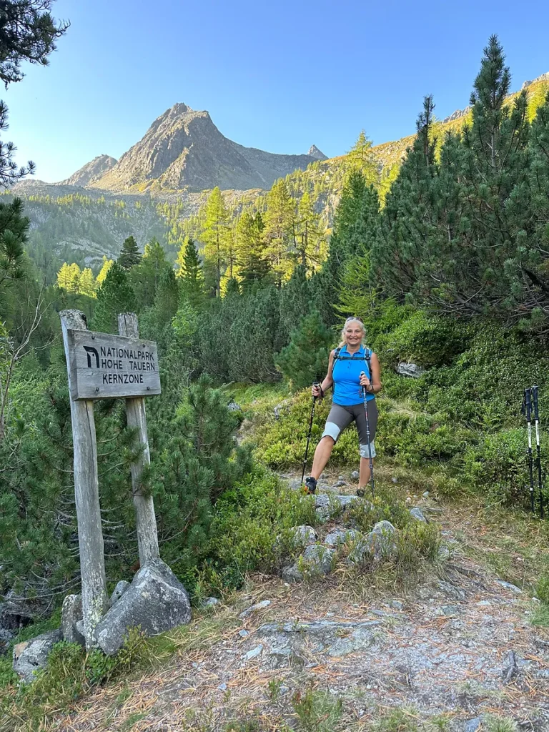 Gerti beim Wandern im Nationalpark Hohe Tauern neben einem Holzschild mit Hinweis auf die Kernzone