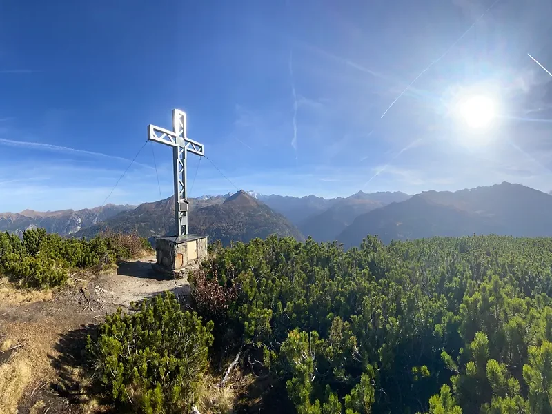 Gipfelkreuz mit weitem Blick auf eine ruhige Wanderlandschaft in Gastein