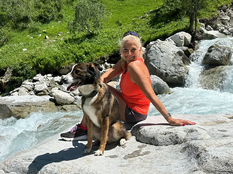 Frau mit Hund bei einer Pause an einem Gebirgsbach in Gastein