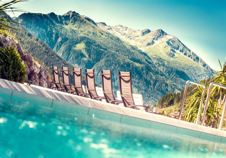 Außenbecken und Sonnenliegen der Felsentherme vor der Bergkulisse