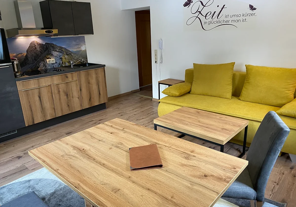 Wohnküche mit Sofa, Esstisch und Küchenzeile im Apartment Großglockner bei GRUBERS