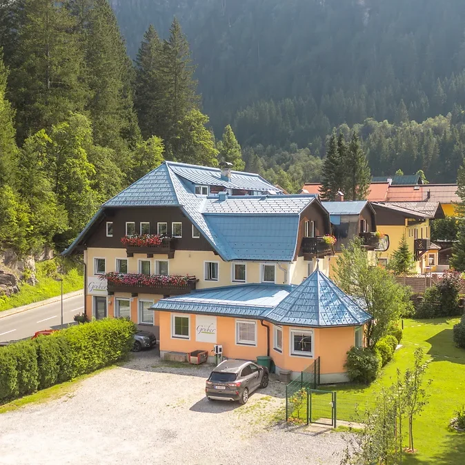 Blick auf das GRUBERS Hotel-Apartments in Bad Gastein mit direktem Einstieg in den Wald und die umliegenden Berge
